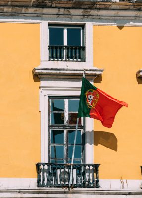 Photo: Portuguese flag on yellow facade reflecting on window. Credit: Alexandre Rotenberg/Alamy