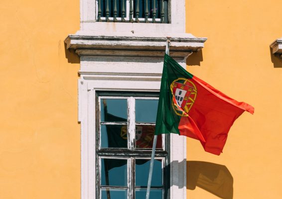 Photo: Portuguese flag on yellow facade reflecting on window. Credit: Alexandre Rotenberg/Alamy