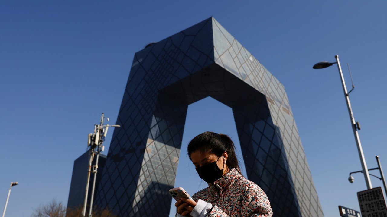 Photo: A woman holding a mobile phone walks past the CCTV headquarters, the home of Chinese state media outlet CCTV and its English-language sister channel CGTN, in Beijing, China February 5, 2021. Credit: REUTERS/Carlos Garcia Rawlins