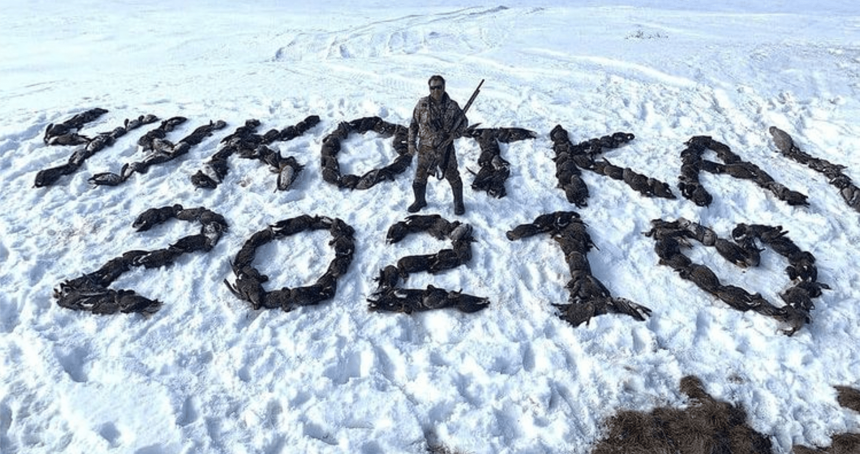 Photo: Aleksandr Kramarenko holding a hunting rifle and standing in the middle of a snowy field where what appeared to be almost 200 dead wild birds were arranged to spell out the words "Chukotka 2021". Credit: @hunting_in_siberia/Instagram via RadioFreeEurope