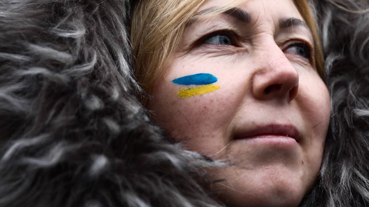 Photo: A woman with an Ukrainian flag painted on her cheek attends a protest against Russian agression to the Ukraine, in Krakow, Poland on February 20, 2022. The demonstration is organized as the Russian-Ukrainian border tension continues. Credit: Jakub Porzycki/NurPhoto