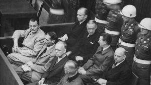 Photo: Nuremberg Trials. Defendants in their dock, circa 1945-1946. (in front row, from left to right): Hermann Göring, Rudolf Heß, Joachim von Ribbentrop, Wilhelm Keitel (in second row, from left to right): Karl Dönitz, Erich Raeder, Baldur von Schirach, Fritz Sauckel. Credit: Wikimedia Commons