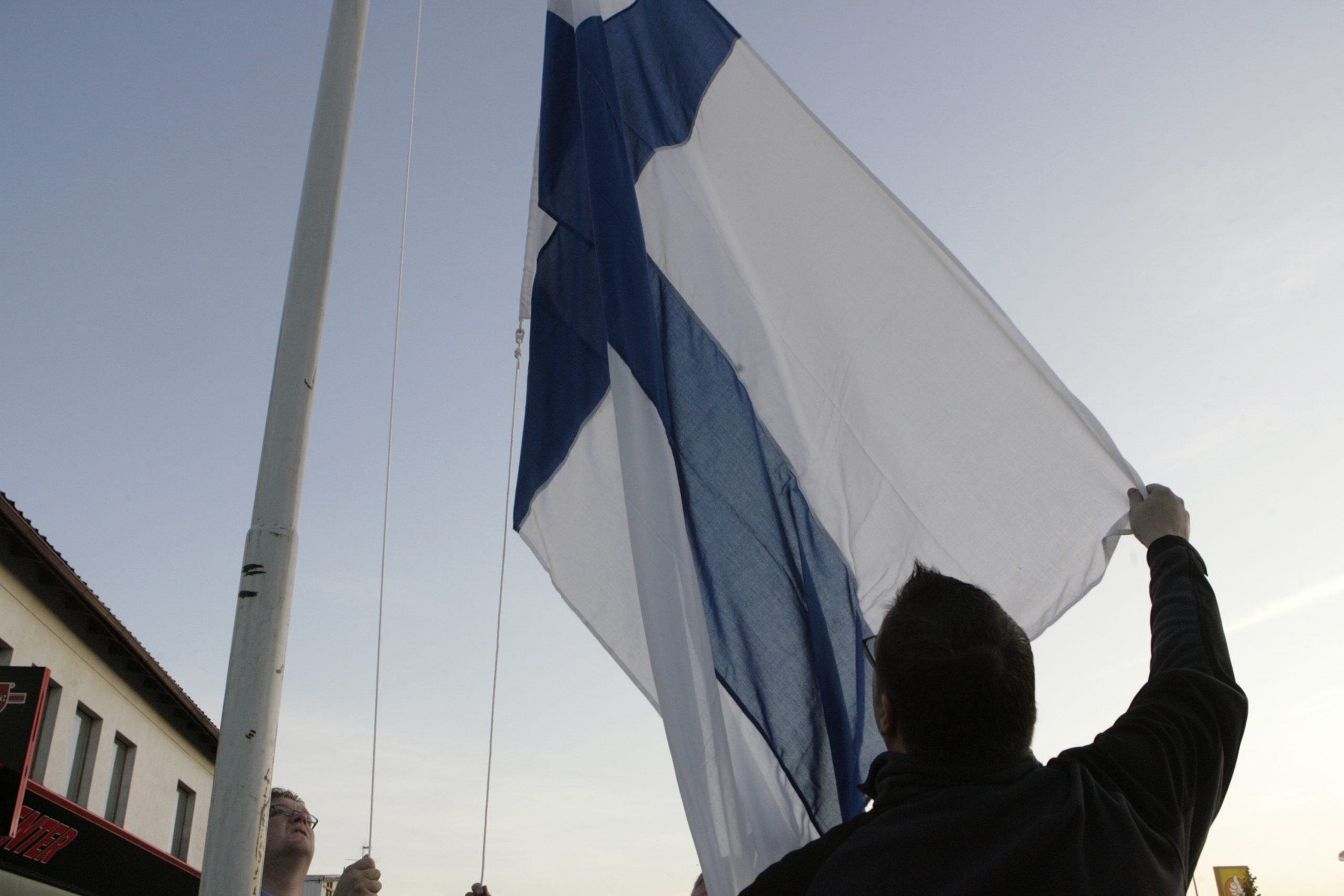 Residents lower the Finnish flag to half-mast.  REUTERS/Ints Kalnins (FINLAND)
