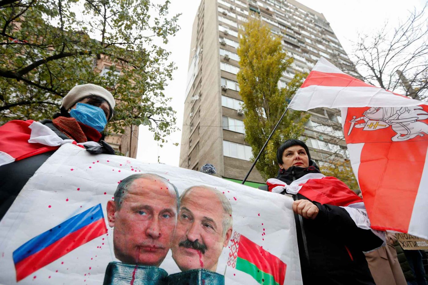 Photo: People gather to mourn the death of Belarusian anti-government protester Roman Bondarenko, who was allegedly beaten by the country's security forces in Minsk, outside the Belarusian embassy in Kyiv, Ukraine November 13, 2020. A placard displays images depicting Russian President Vladimir Putin and Belarusian President Alexander Lukashenko. Credit: REUTERS/Valentyn Ogirenko
