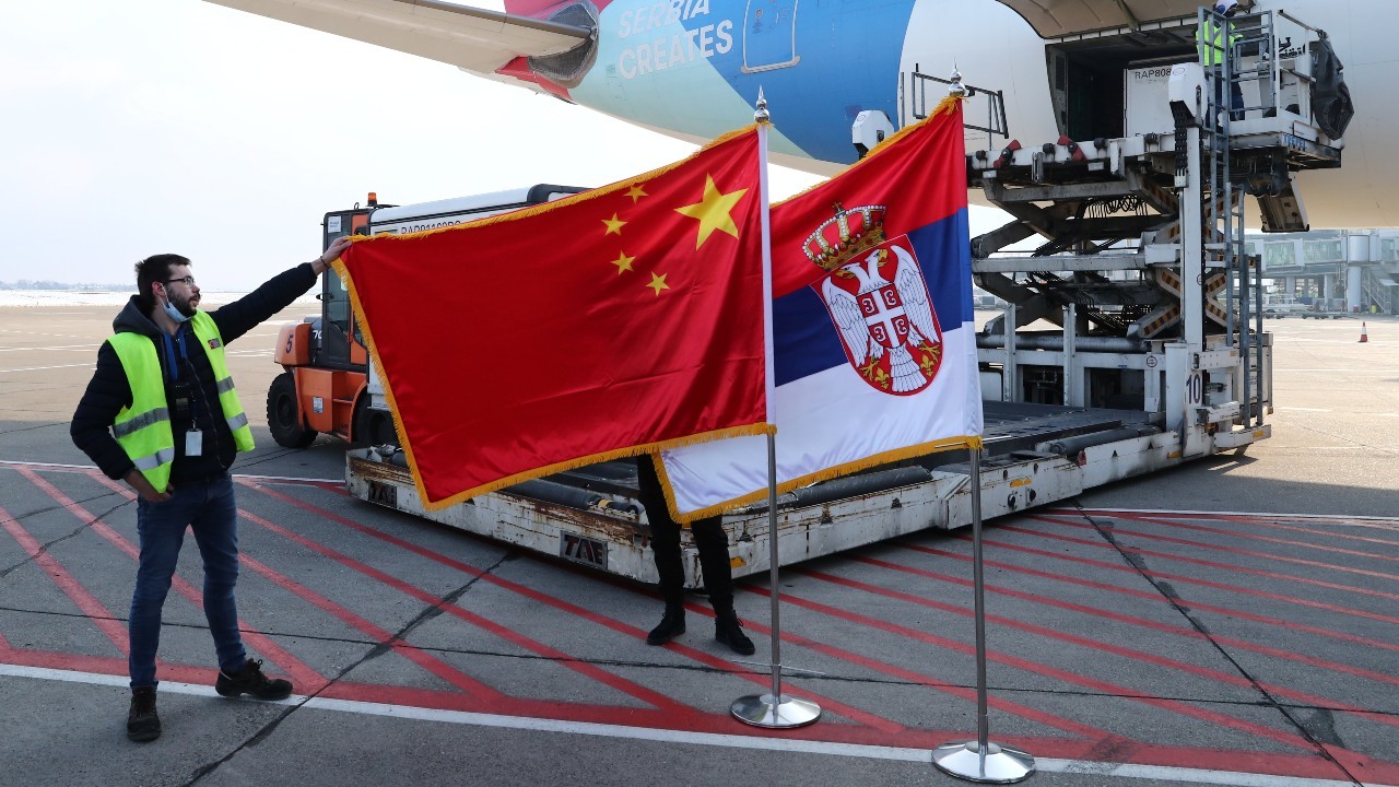 Photo: A man holds China's flag next to Serbia's flag as a plane transporting one million doses of Sinopharm's China National Biotec Group (CNBG) vaccines for the coronavirus disease (COVID-19) arrives at Nikola Tesla Airport in Belgrade, Serbia, January 16, 2021. Credit: REUTERS/Marko Djurica