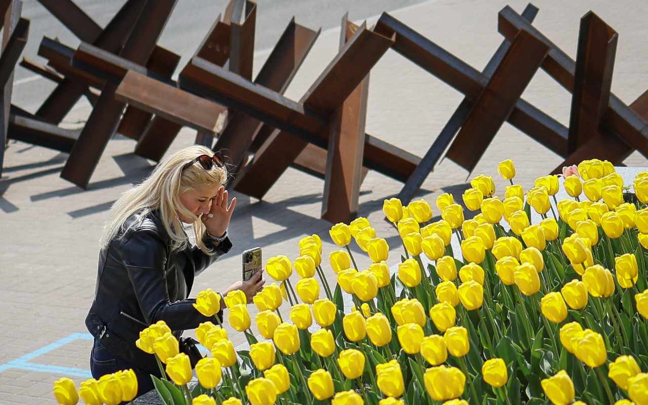 Photo: A woman takes a picture of the blooming tulips, near an anti-tank constructions, amid Russia's invasion of Ukraine, in central Kyiv, Ukraine May 2, 2022. Credit: REUTERS/Gleb Garanich.