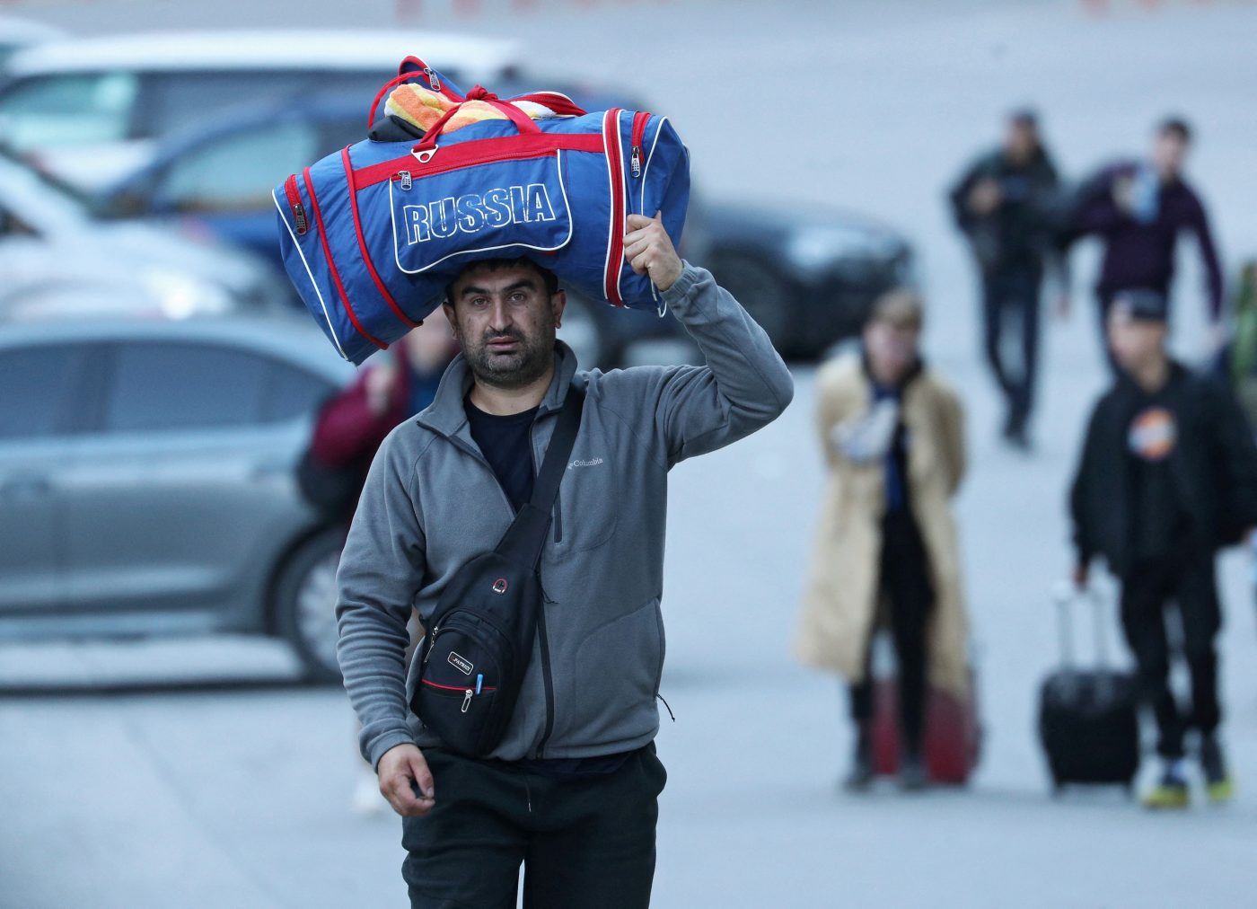 Photo: A man carries a bag on his head as travellers from Russia cross the border to Georgia at the Zemo Larsi/Verkhny Lars station, Georgia September 26, 2022. Credit: REUTERS/Irakli Gedenidze