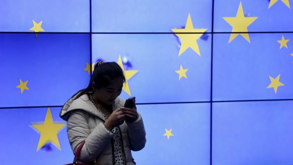 Photo: A visitor uses her mobile phone in front of an electronic board in the atrium of the European Council building in Brussels, Belgium, February 2, 2016. Credit: REUTERS/Francois Lenoir.