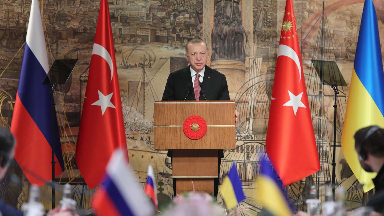Photo: President Recep Tayyip Erdoğan standing between Turkish, Russian, and Ukrainian flags. Credit: @RTErdogan via Twitter.