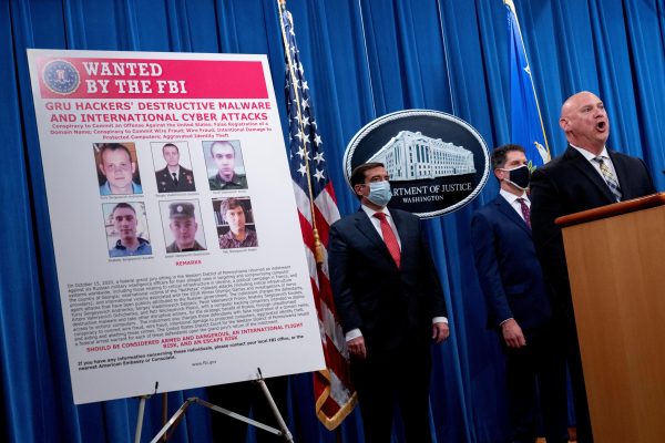 Photo: A poster showing six wanted Russian military intelligence officers is displayed as U.S. FBI Special Agent in Charge of the Pittsburgh field office Michael Christman, accompanied by Assistant Attorney General for the National Security Division John Demers, and FBI Deputy Director David Bowdich, speaks at a news conference at the Department of Justice, in Washington, U.S., October 19, 2020. Credit: Andrew Harnik/Pool via REUTERS