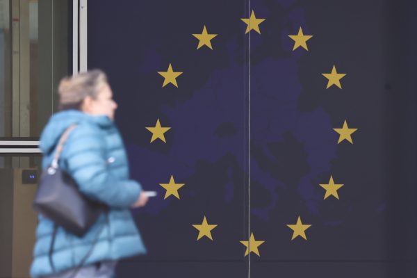Photo: A person passes by the European Union flag on the Berlaymont in Brussels, Belgium on October 11, 2022. Photo:Jakub Porzycki/NurPhoto
