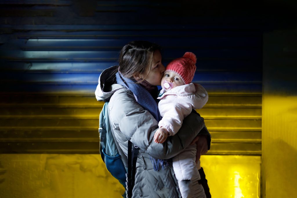 Photo: A loving mother holding her child in her arms in the underground shelter. Credit: Marko Subotin / Alamy Stock Photo