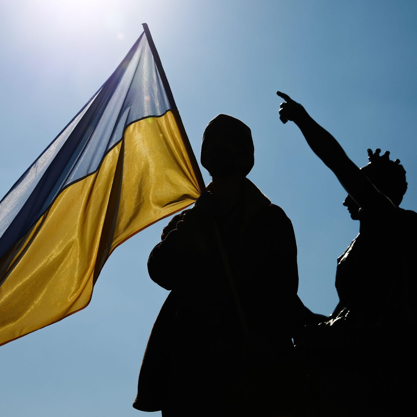 Photo: A protester holds an Ukrainian flag as he stand on the monument during demonstration in Krakow, Poland on March 17, 2022. Credit: Jakub Porzycki/NurPhoto