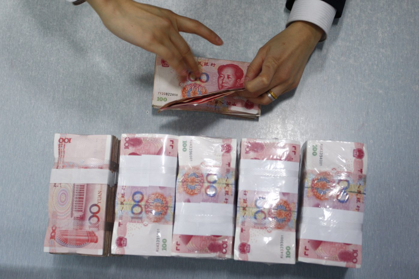 Photo: An employee counts Renminbi banknotes at a branch of Suining Commercial Bank, Sichuan province February 4, 2010. Credit: REUTERS/Stringer