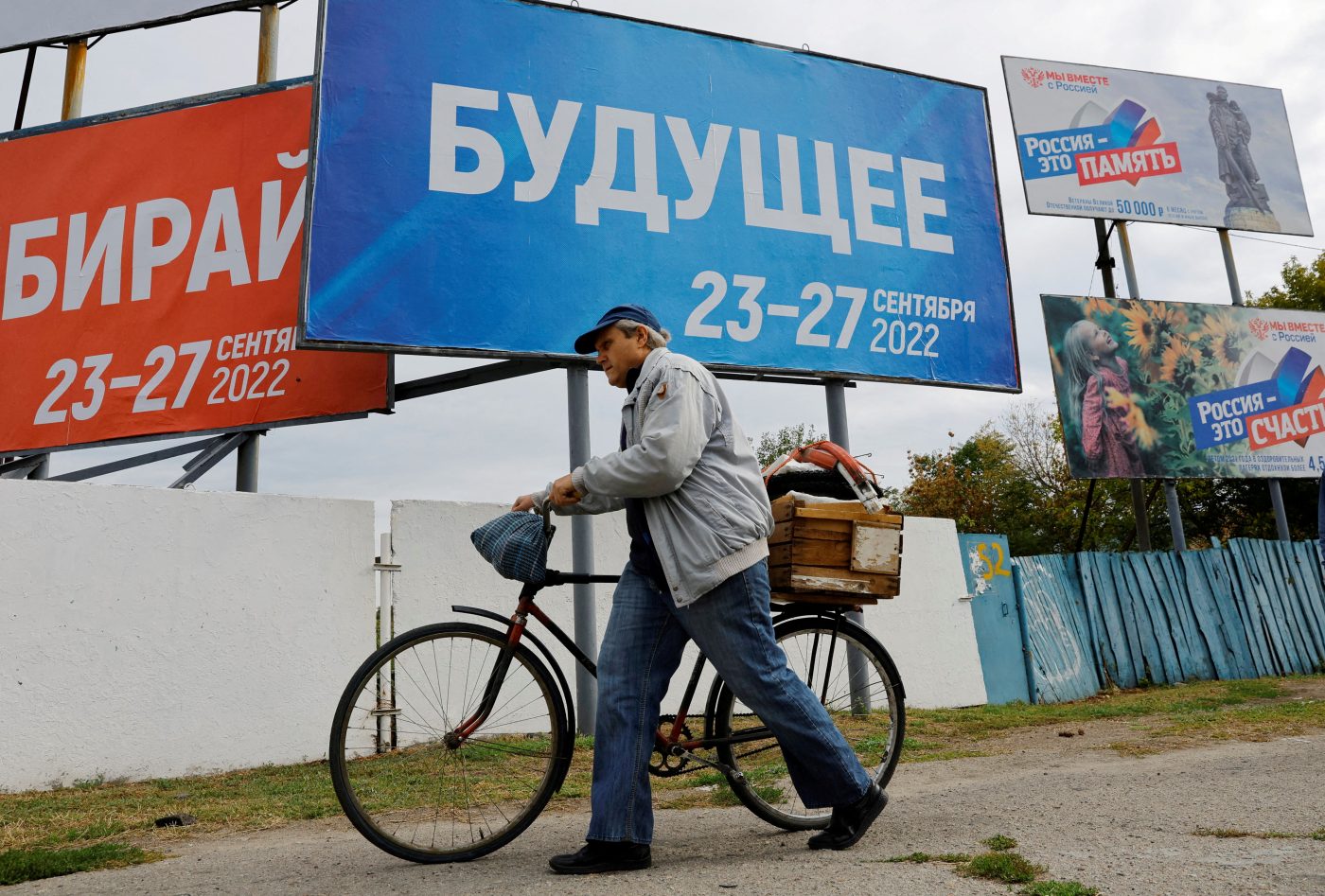 Photo: A man walks with his bicycle past banners informing about a referendum on the joining of Russian-controlled regions of Ukraine to Russia, in the Russian-controlled city of Melitopol in the Zaporizhzhia region, Ukraine September 26, 2022. The banner (C) reads: "Future. 23-27 September 2022". Credit: REUTERS/Alexander Ermochenko