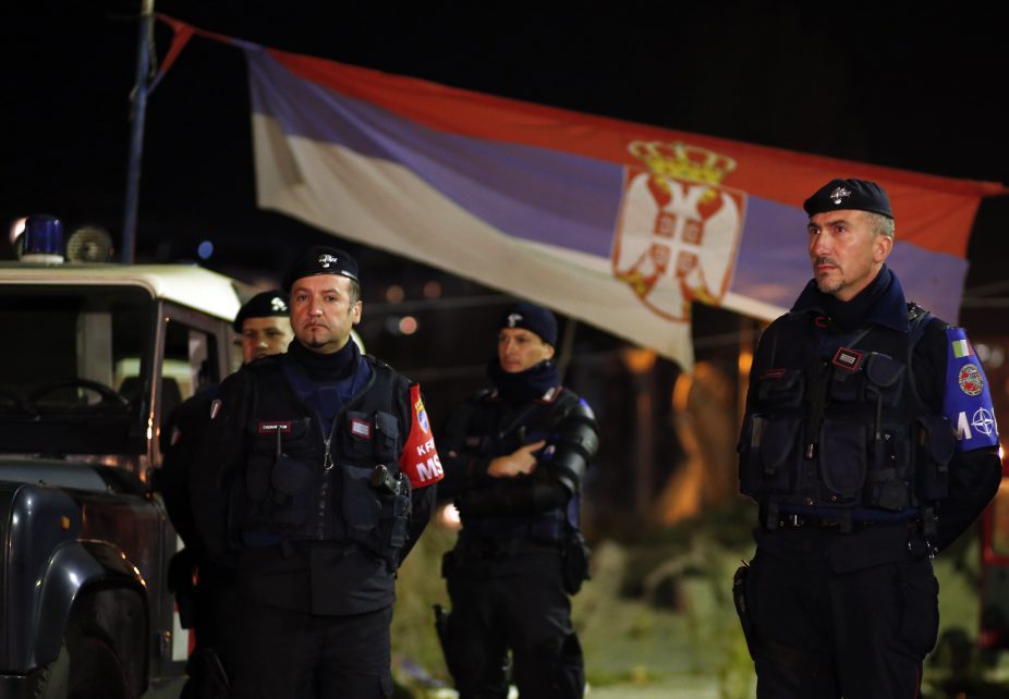 Photo: Italian Carabinieri, who are members of the NATO Kosovo Force (KFOR), stand in front of a Serbian national flag as they secure the main bridge in the northern part of the ethnically-divided town of Mitrovica, November 3, 2013. Credit: REUTERS/Marko Djurica