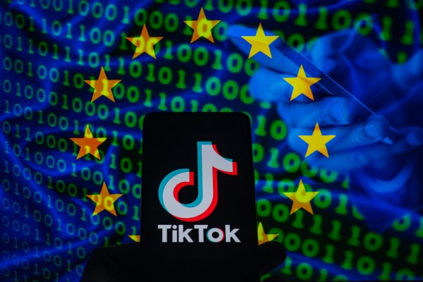 Photo: TikTok icon displayed on a phone screen with in the background European Union flag with cyber code, seen in this photo illustration. on 23 February 2023 in Brussels, Belgium. Credit: Jonathan Raa/NurPhoto