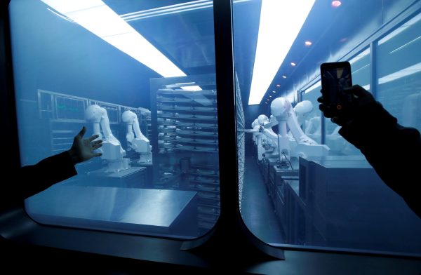 Photo: A customer takes a picture as robotic arms collect pre-packaged dishes from a cold storage, done according to the diners' orders, at Haidilao's new artificial intelligence hotpot restaurant in Beijing, China, November 14, 2018. Credit: REUTERS/Jason Lee
