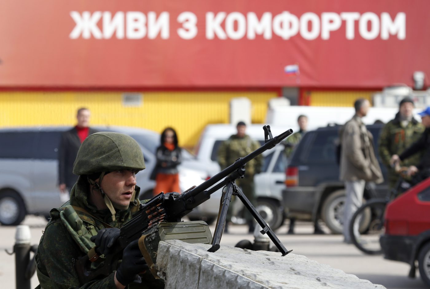Photo: An armed man, believed to be a Russian serviceman, guards near the naval headquarters in Sevastopol, March 19, 2014. Around a dozen Ukrainian servicemen, unarmed and in civilian clothes, walked out of the Ukrainian naval headquarters in the Crimean port of Sevastopol on Wednesday after it was taken over by pro-Russian forces, a Reuters witness said. The words in the background read,"Live with comfort". Credit: REUTERS/Vasily Fedosenko