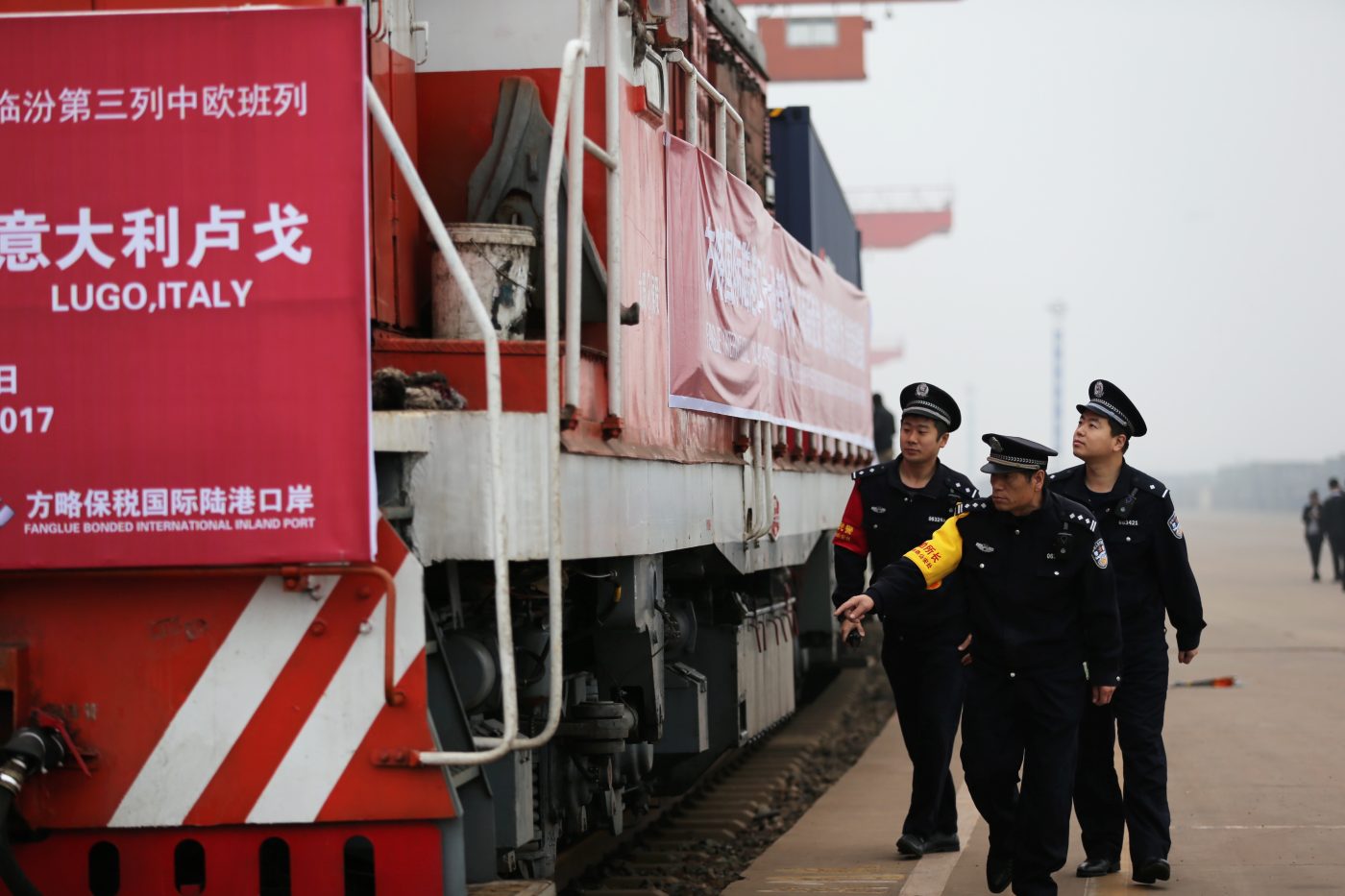Photo: Chinese police officers check a freight train of China Railway Express running from Linfen to Italy's Lugo before departing from the north Houma station in Linfen city, north China's Shanxi province, 25 October 2017. A freight train headed for Lugo, Italy, had departed from the north Houma station in Linfen city, north China's Shanxi province, 25 October 2017. This freight train will travel along the Silk Road Economic Belt through Romania, Poland, Czech Republic and France. Thanks to the freight line, transport times and transport costs have been drastically reduced. Credit: Oriental Image via Reuters Connect