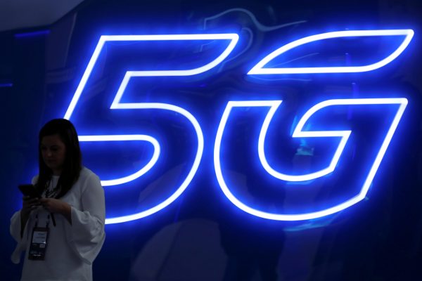 Photo: A woman looks at her mobile phone next to a 5G sign at the Mobile World Congress in Barcelona, Spain, February 25, 2019. Credit: REUTERS/Sergio Perez/File Photo