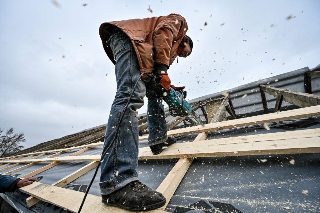 Photo: A worker saws a wood plank on the roof as a 70-year-old building situated on the premises of a military hospital is being repaired to admit more wounded soldiers, Zaporizhzhia, southeastern Ukraine. Credit: Dmytro Smolyenko via Reuters Connect