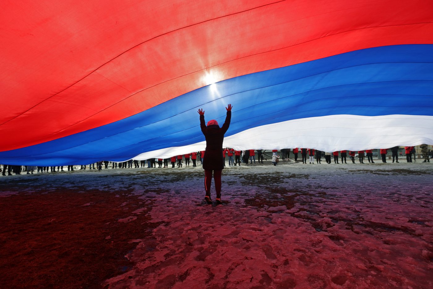 Photo: A participant stands under a giant Russian national flag during an event marking the ninth anniversary of Russia's annexation of Crimea, in Saint Petersburg, Russia March 18, 2023. Credit: REUTERS/Anton Vaganov