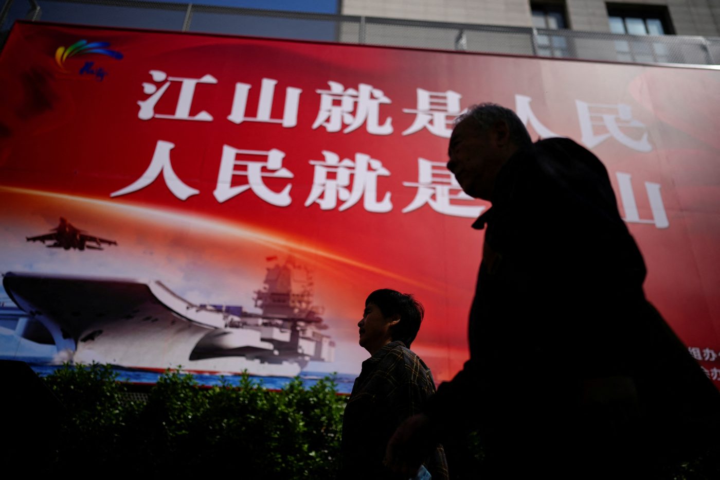 Photo: People walk on a street in front of a large propaganda poster in Shanghai, China, April 10, 2023. Credit: REUTERS/Aly Song