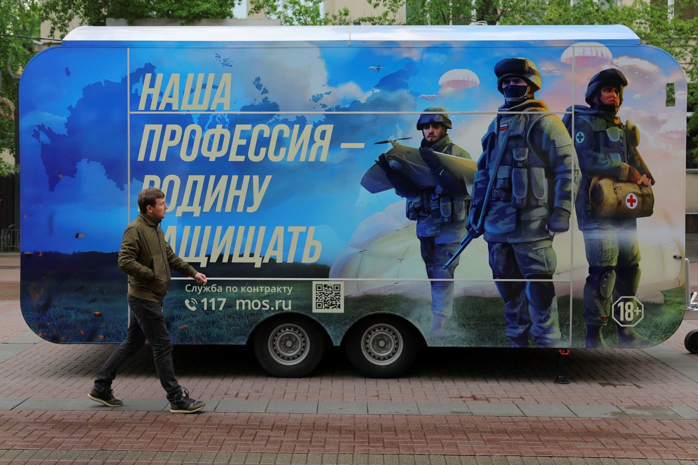 Photo: A pedestrian walks past a mobile recruitment point located to promote service in the Russian army and invite volunteers to sign a contract with the defence ministry, in a street in Moscow, Russia, May 3, 2023. A slogan reads: "Our profession is to defend fatherland". Credit: REUTERS/Evgenia Novozhenina