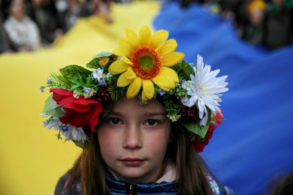 Photo: A young girl looks at a camera as people carry a huge Ukrainian flag as they participate in a peaceful demonstration "Solidarity with Ukraine" in Krakow, Poland, April 24, 2022. Credit: Jakub Wlodek/Agencja Wyborcza.pl via REUTERS