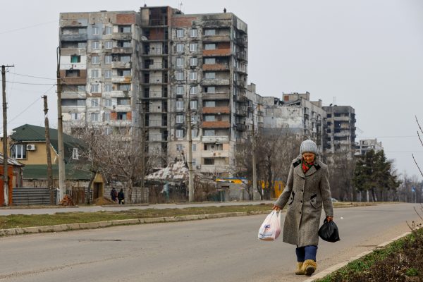 Photo: A local resident walks near multi-storey apartment blocks, which were damaged in the course of Russia-Ukraine conflict, in Mariupol, Russian-controlled Ukraine, March 16, 2023. Credit: REUTERS/Alexander Ermochenko