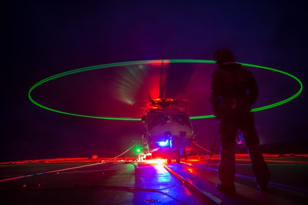 A Royal Netherlands Navy NH-90 prepares to take off at night aboard Standing NATO Maritime Group Two flagship HNLMS De Ruyter October 31, 2018, during NATO exercise Trident Juncture. Credit: NATO via Flickr.