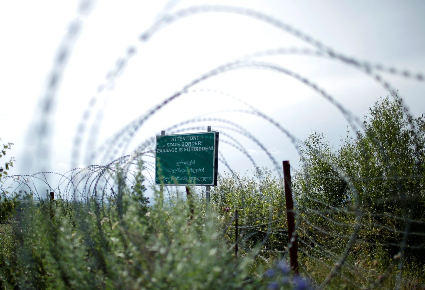 Photo: A border sign is seen behind the barbed wire at the de facto border of Georgia's breakaway region of South Ossetia in Khurvaleti, Georgia, June 18, 2018. Picture taken June18, 2018. Credit: REUTERS/David Mdzinarishvili
