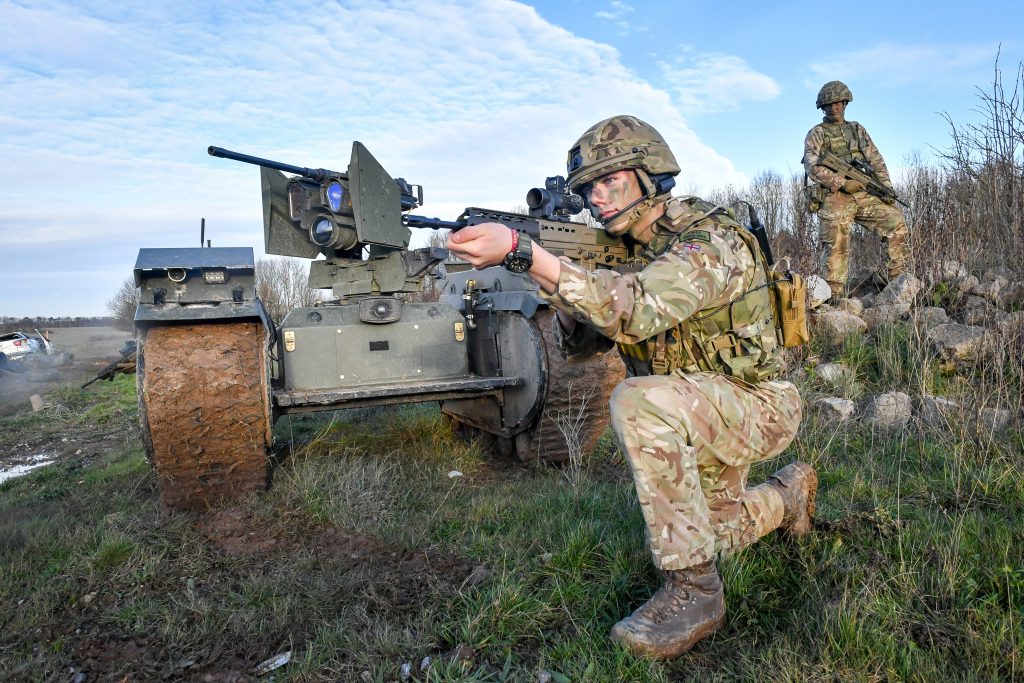 Photo: Soldiers surround a Titan Strike unmanned ground vehicle, equipped with a .50 Caliber machine gun, moves and secures ground on Salisbury Plain during exercise Autonomous Warrior 18, where military personnel, government departments and industry partners are taking part in Exercise Autonomous Warrior, working with NATO allies in a groundbreaking exercise to understand how the military can exploit technology in robotic and autonomous situations. Credit: Ben Birchall/ PA Images.