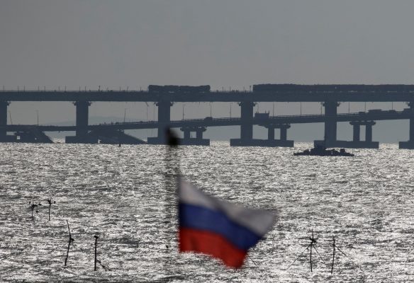 Photo: Russian national flag flies with backdrop of the Kerch bridge after an explosion destroyed part of it, in the Kerch Strait, Crimea, October 8, 2022. Credit: REUTERS/Stringer