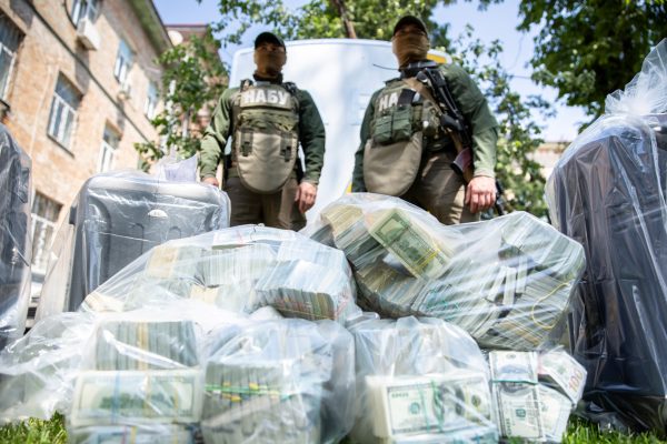 Photo: Officers of the National Anti-Corruption Bureau of Ukraine stand next to plastic bags filled with seized US Dollar banknotes in Kiev, Ukraine, in this handout picture released June 13, 2020. According to the National Anti-Corruption Bureau of Ukraine, some $5 million was offered to anti-corruption officials and a further $1 million was intended for an official acting as a middleman. Credit: Press Service of the National Anti-Corruption Bureau of Ukraine/Handout via REUTERS ATTENTION EDITORS