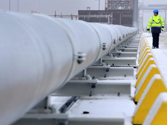 Photo: A worker walks past a gas tube that connects the 'Hoegh Esperanza' Floating Storage and Regasification Unit (FSRU) with main land during the opening of the LNG (Liquefied Natural Gas) terminal in Wilhelmshaven, Germany, December 17, 2022. Credit: Michael Sohn/Pool via REUTERS