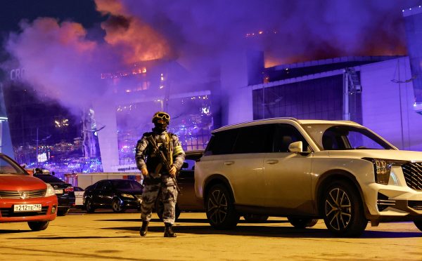 Photo: A Russian law enforcement officer walks at a parking area near the burning Crocus City Hall concert venue following a shooting incident, outside Moscow, Russia, March 22, 2024. Credit: REUTERS/Maxim Shemetov