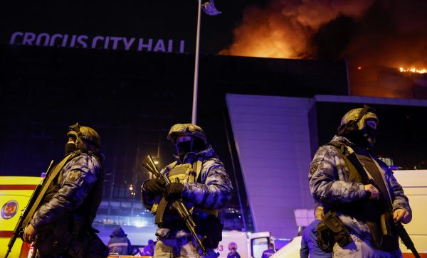 Photo: Russian law enforcement officers stand guard near the burning Crocus City Hall concert venue following a reported shooting incident, outside Moscow, Russia, March 22, 2024. Credit: REUTERS/Maxim Shemetov