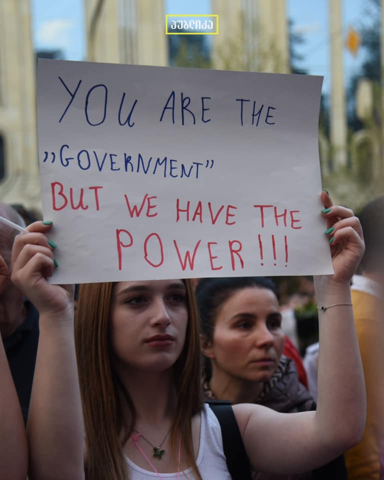 Photo: Woman holding sign at protest in Georgia. Credit: Publica