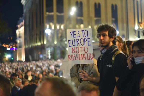 Photo: Man holding sign at protest in Georgia. Credit: Publica