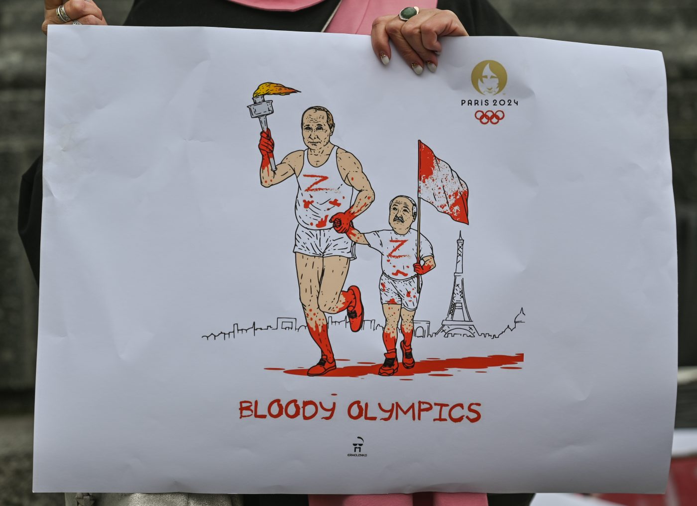 Photo: A protester in Krakow holds a powerful poster with Putin and Lukashenko's images, featuring an Olympic torch covered in blood and the words 'Bloody Olympics', on March 31, 2023, in Krakow, Poland. On the 401st day of the Russian invasion of Ukraine, activists from Ukraine and Belarus protested again the ongoing conflict and asked for the ban of Russian and Belarussian athletes at the 2024 Summer Olympics in Paris. Credit: Artur Widak/NurPhoto