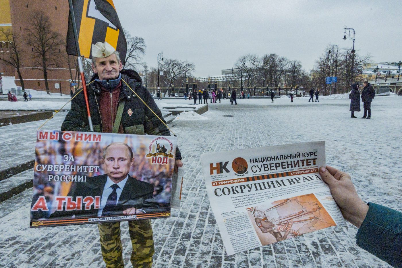 Photo: A Putin supporter distributes war propaganda in the Kremlin with a huge banner with a Putin photo saying ''we are with him, for the russian soveranity, and you?''. The propaganda paper says ''we will destroy the enemy'', in reference to the U.S. and the war in Ukraine. Credit: Celestino Arce/NurPhoto