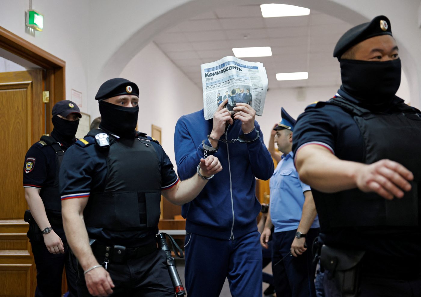Photo: Timur Ivanov, Russian Deputy Defence Minister, who was dismissed from his post and taken into custody on suspicion of accepting bribes, covers his face with a newspaper as he is escorted inside a courthouse before a hearing in Moscow, Russia June 20, 2024. Credit: REUTERS/Yulia Morozova
