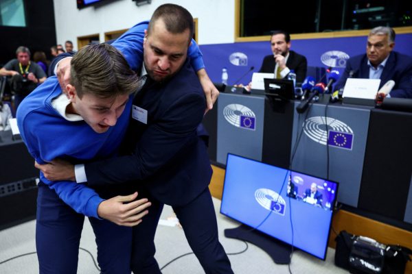 Photo: In Hungary, a security member grabs a protester as Hungarian Prime Minister Viktor Orban speaks during a press conference with MEP Kinga Gal, Vice-President of Patriots for Europe Group, at the European Parliament in Strasbourg, France October 8, 2024. Credit: REUTERS/Yves Herman