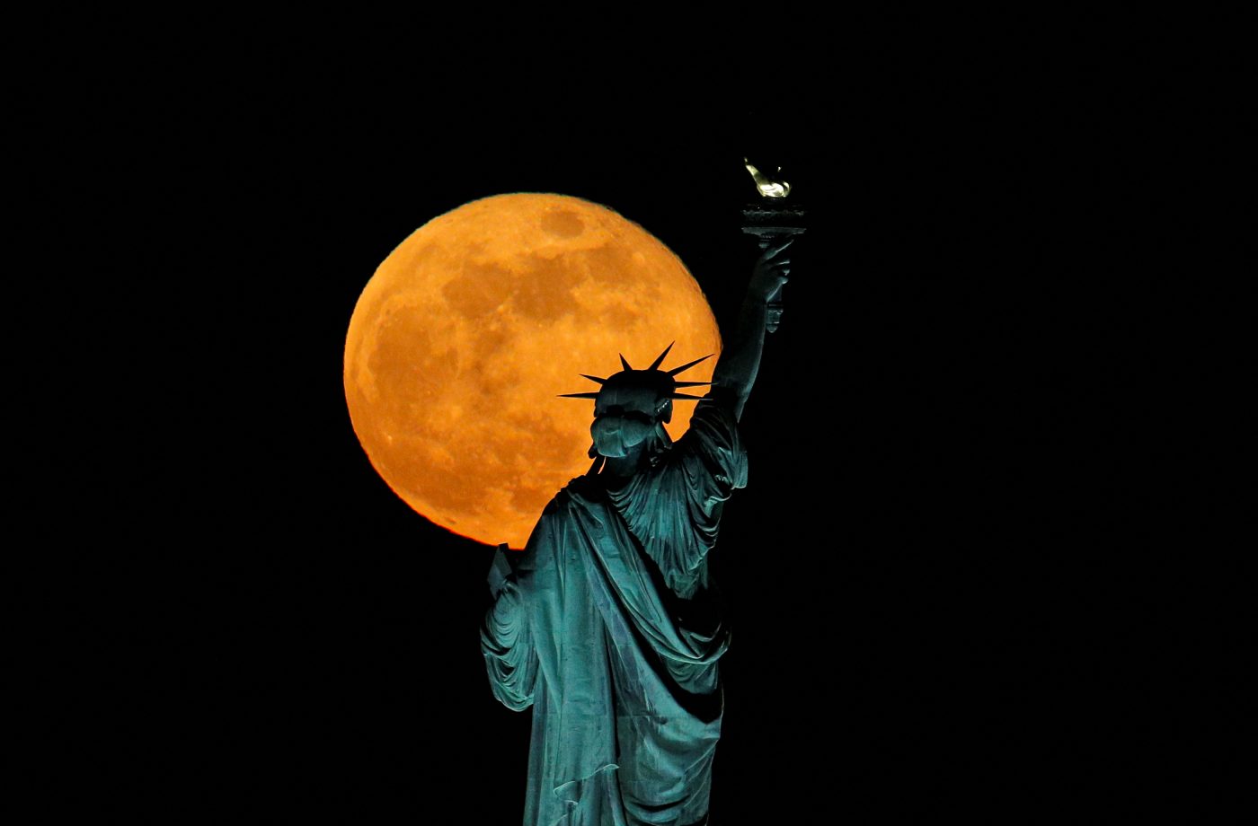 Photo: In America, he full moon, also known as the Supermoon or Flower Moon, rises above the Statue of Liberty, as seen from Jersey City, New Jersey, US in North America. May 7, 2020. Credit: REUTERS/Brendan McDermid