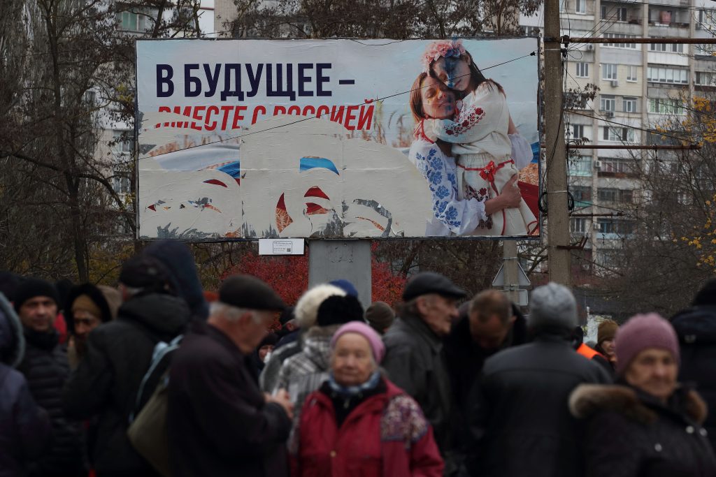Photo: People wait for the distribution of humanitarian aid, with a pro-Russian billboard in the background, after Russia's military retreat from Kherson, Ukraine November 22, 2022. Credit: REUTERS/Murad Sezer