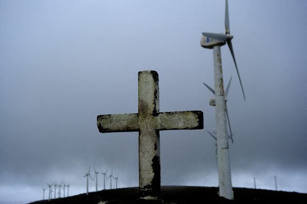 Photo: A cross is pictured in front of wind turbines surrounded by fog at a wind farm in the Serra da Capelada, near Ferrol, Galicia, Spain April 13, 2023. Credit: REUTERS/Nacho Doce