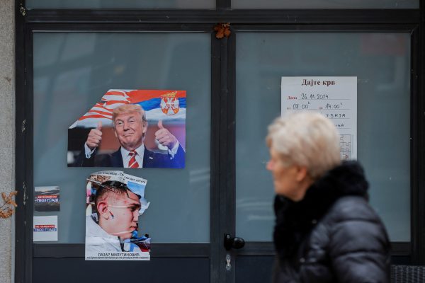 Photo: A woman walks near a poster showing U.S. President Donald Trump with Serbian a flag, in Mitrovica, Kosovo, in the Balkans on January 15, 2025. Credit: REUTERS/Valdrin Xhemaj