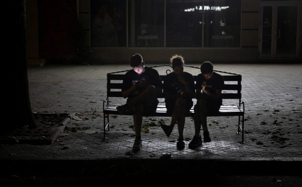 Photo: People use their phones in a poorly lit street during an electricity blackout in Mykolaiv, Ukraine, amid Russia's attack on Ukraine, July 4, 2024. Credit: REUTERS/Thomas Peter